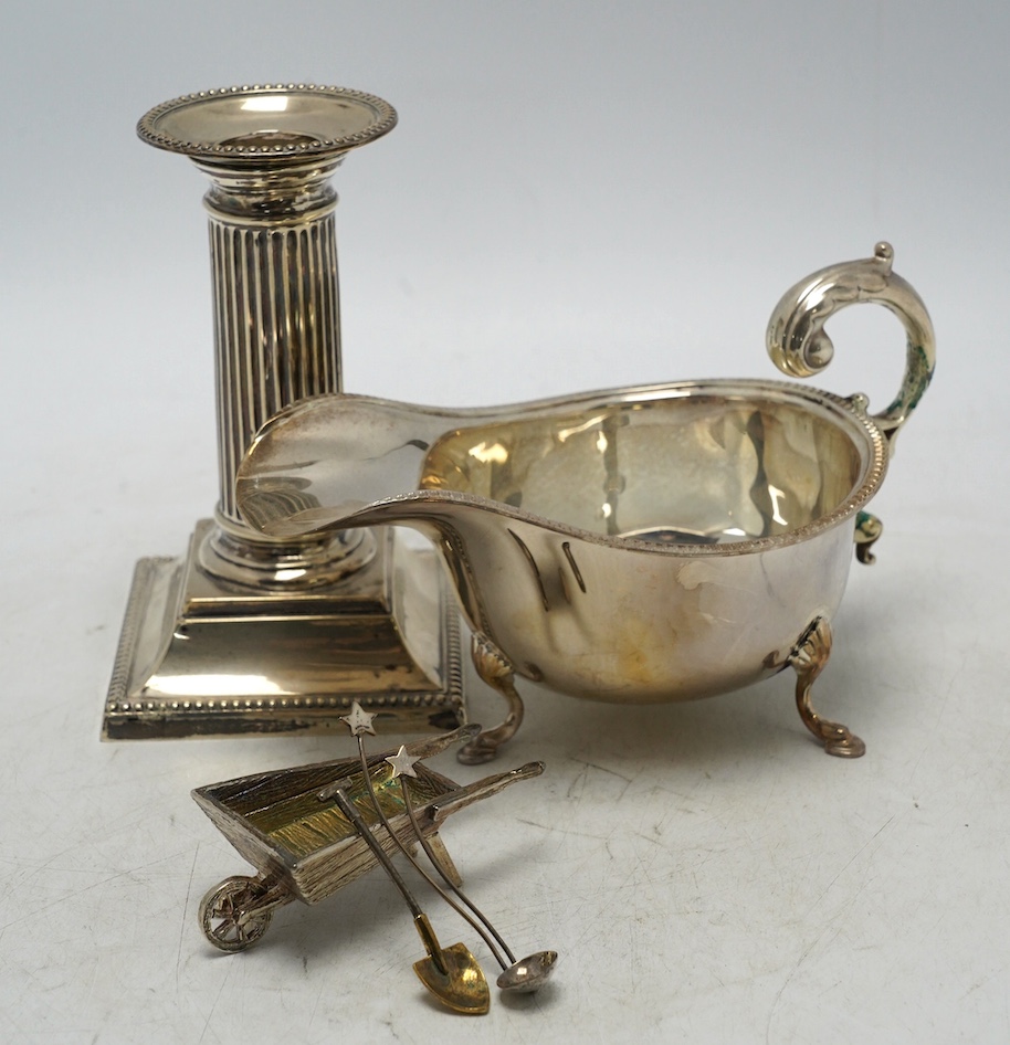 A late Victorian silver dwarf candlestick by Edward Hutton, London, 1893, 12.8cm, a silver sauceboat and three other items. Condition - fair